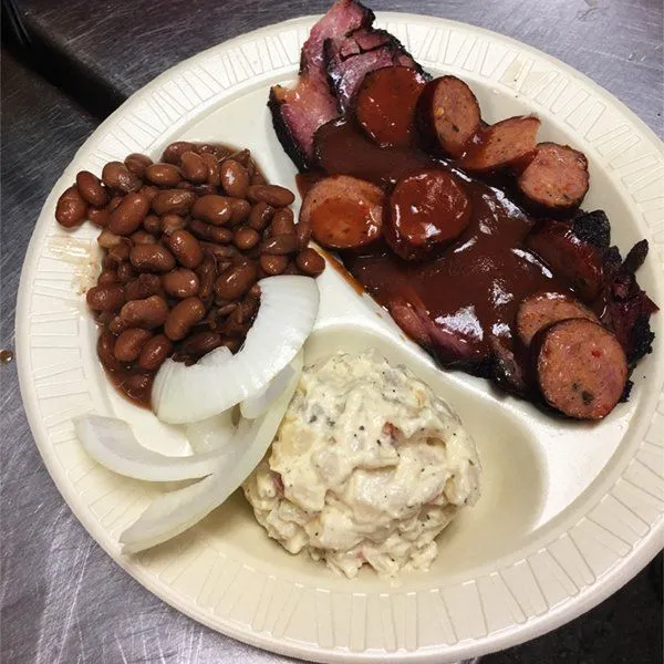 The Sticks BBQ catering spread — sliced brisket, sausage links, pinto beans, and scratch-made sides in Brownwood TX